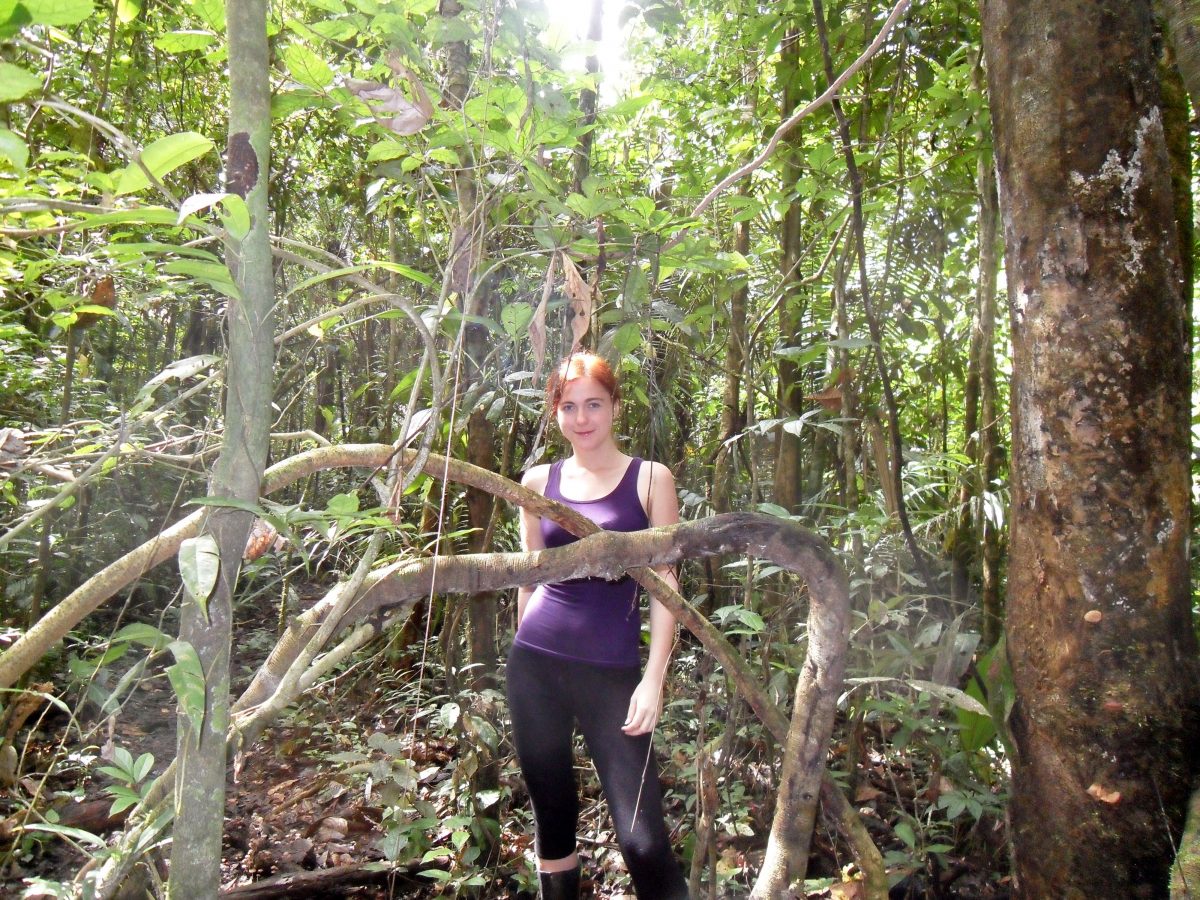 A women stands amongst dense foliage on an amazon jungle tour from  Ecuador