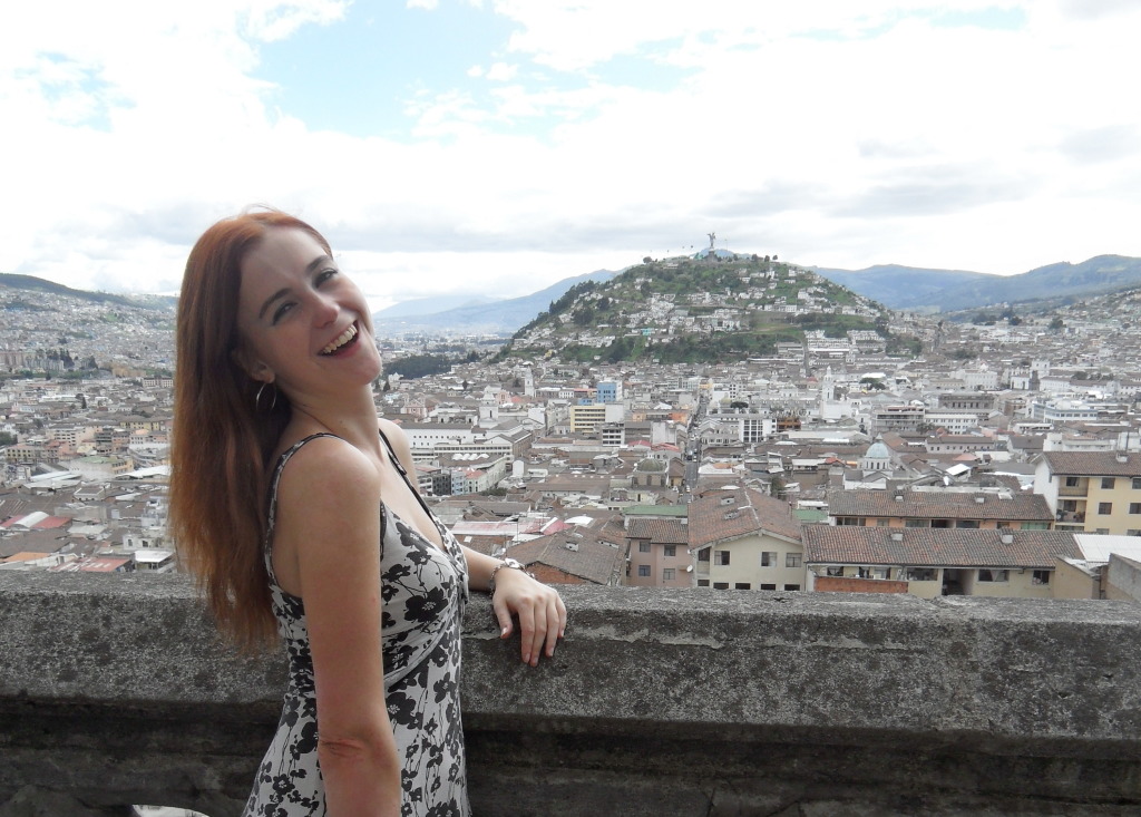 Woman posed in front of a panoramic view of Quitos which includes the popular viewpoint, Mirador de Panecillo