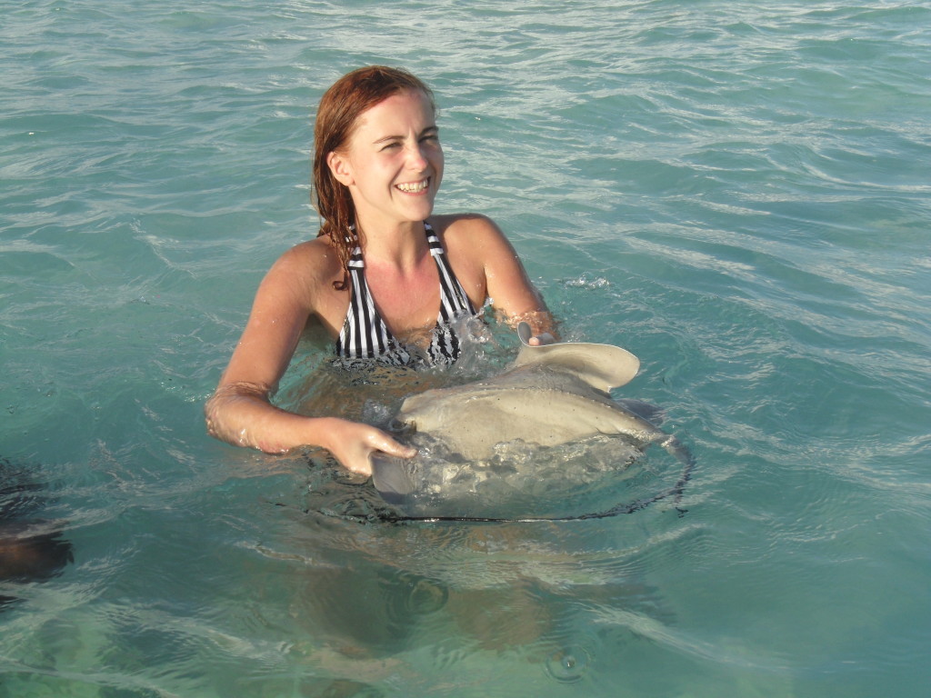 A joyful tourist interacting with a stingray in the shallow, sparkling waters of San Andres Island, representing the unique wildlife encounters and marine activities available to visitors.