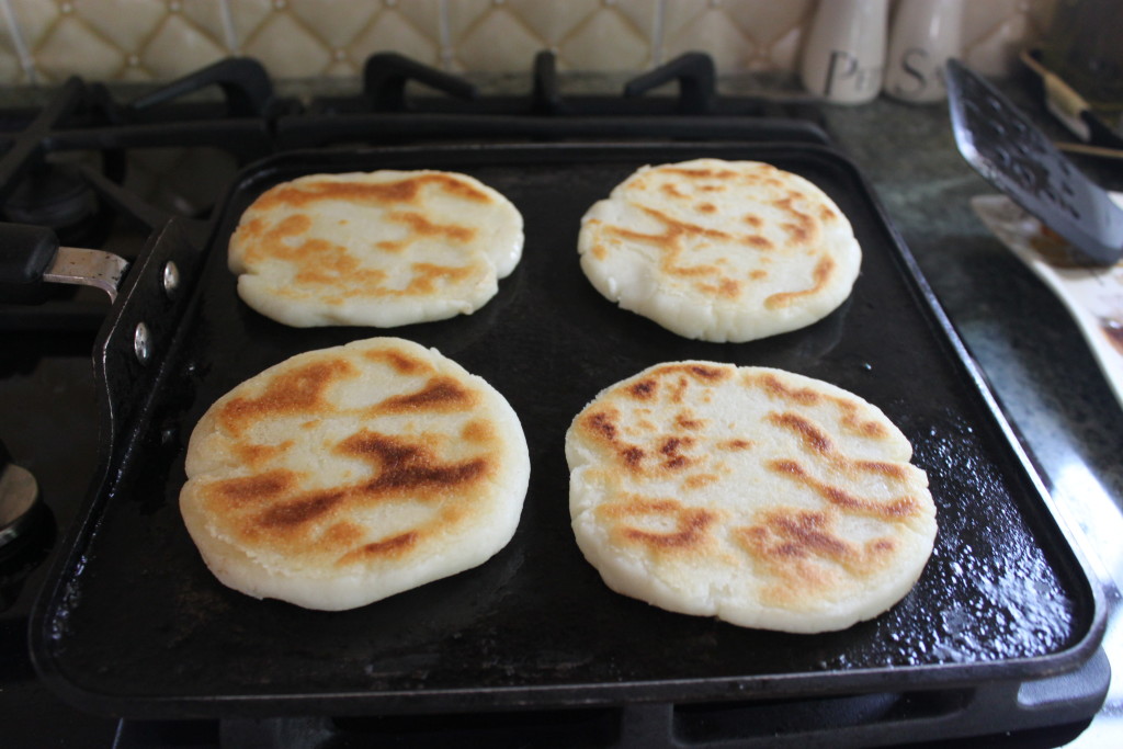 Traditional Colombian arepas cooking on a griddle, a common culinary delight in San Andres Island, suggesting the rich flavors and local dishes travelers can savor.