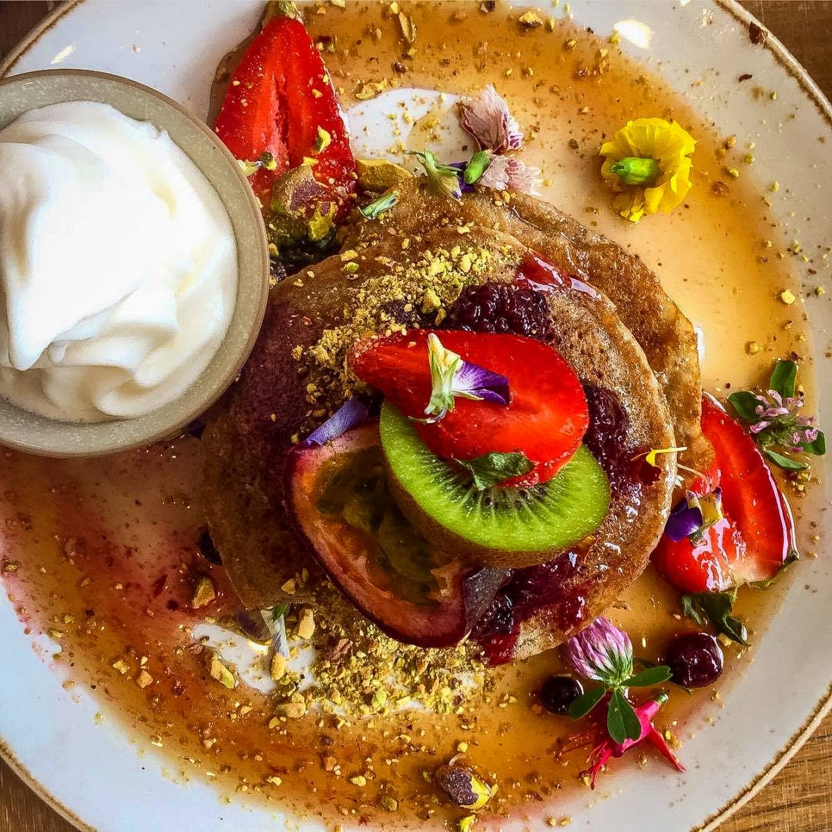 Gourmet pancakes adorned with fresh fruit and edible flowers, showcasing the culinary delights awaiting those moving to Sydney, Australia.