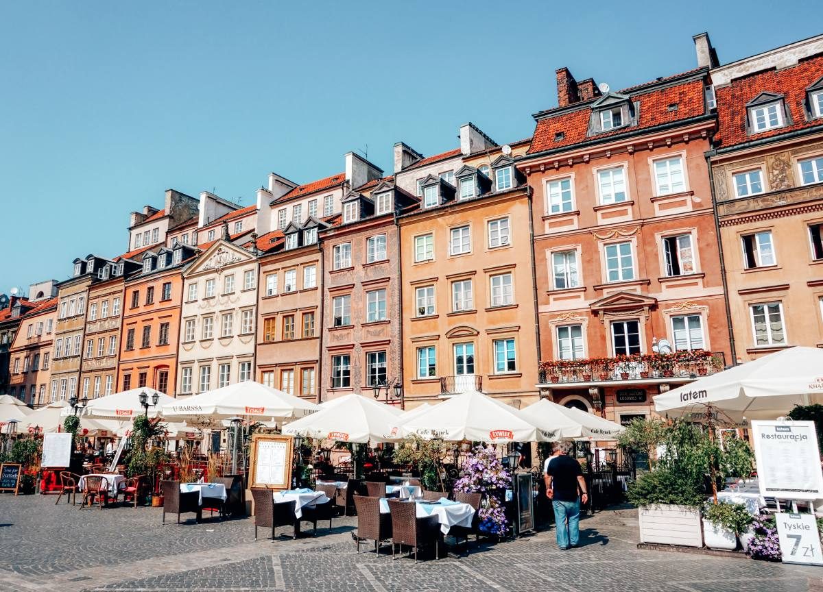 The charming old town square in Warsaw, lined with colorful buildings and outdoor cafés, is a vibrant place to visit in Poland.
