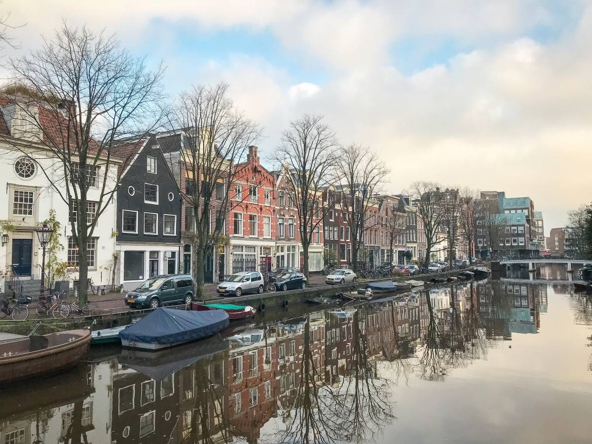 Calm waters of an Amsterdam canal with lined boats and traditional Dutch architecture in Amsterdam Oud Zuid, a great place where to stay in Amsterdam.