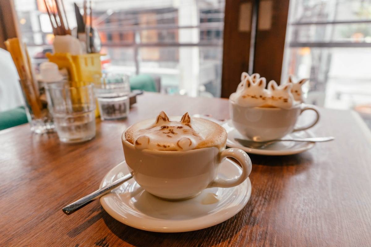 Artistic cat-themed latte art in a cozy 3D Tokyo café.
