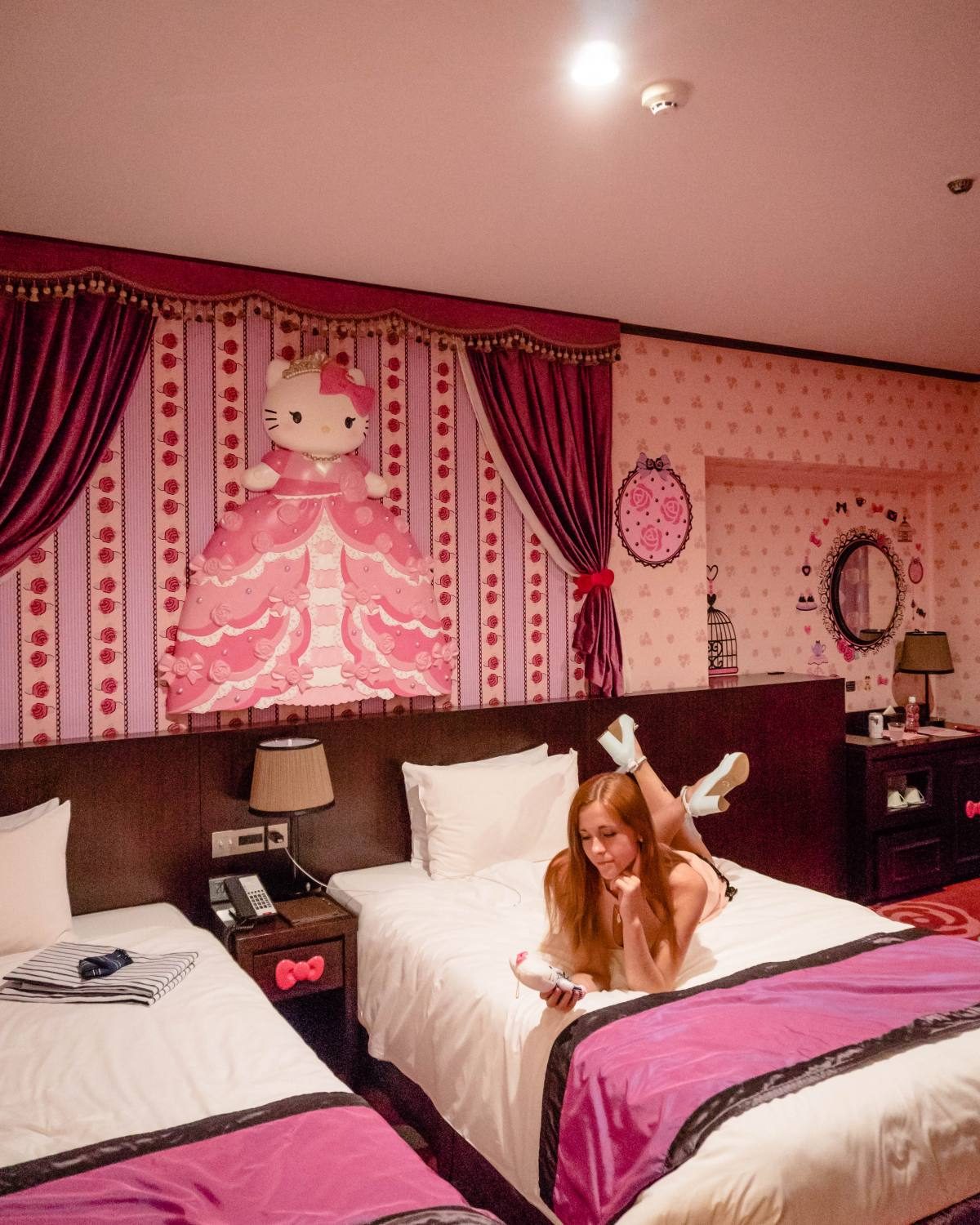 Woman enjoying a stay in a vibrant Hello Kitty-themed hotel room in Tokyo.
