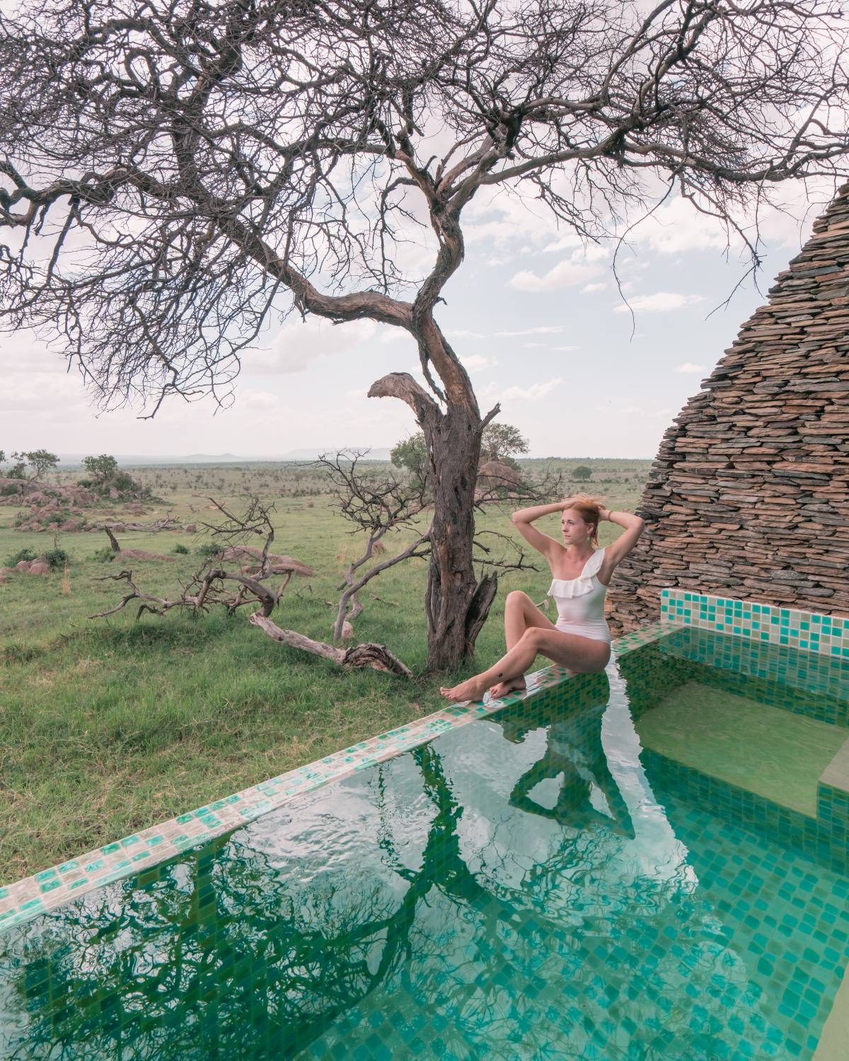 Lady in an affordable Vero Moda white swimsuit sitting next to a swimming pool.