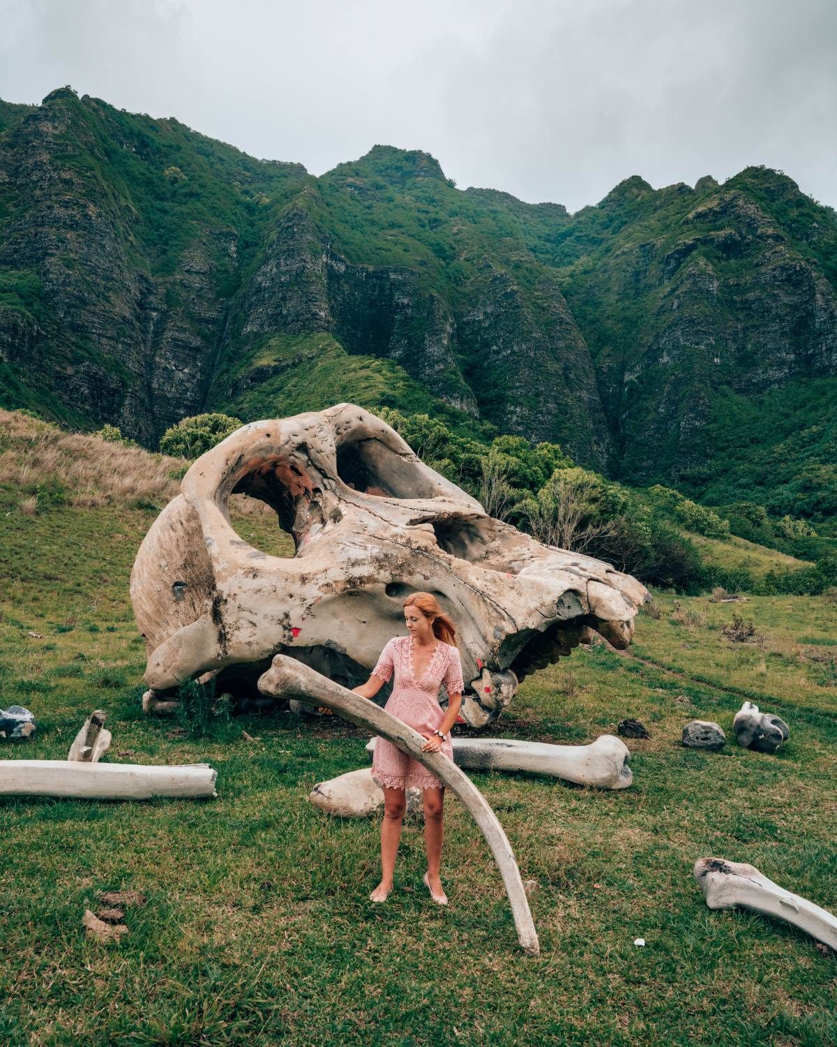 Woman standing by a large skull in a lush green valley, a unique place to explore while traveling in the US with a baby.