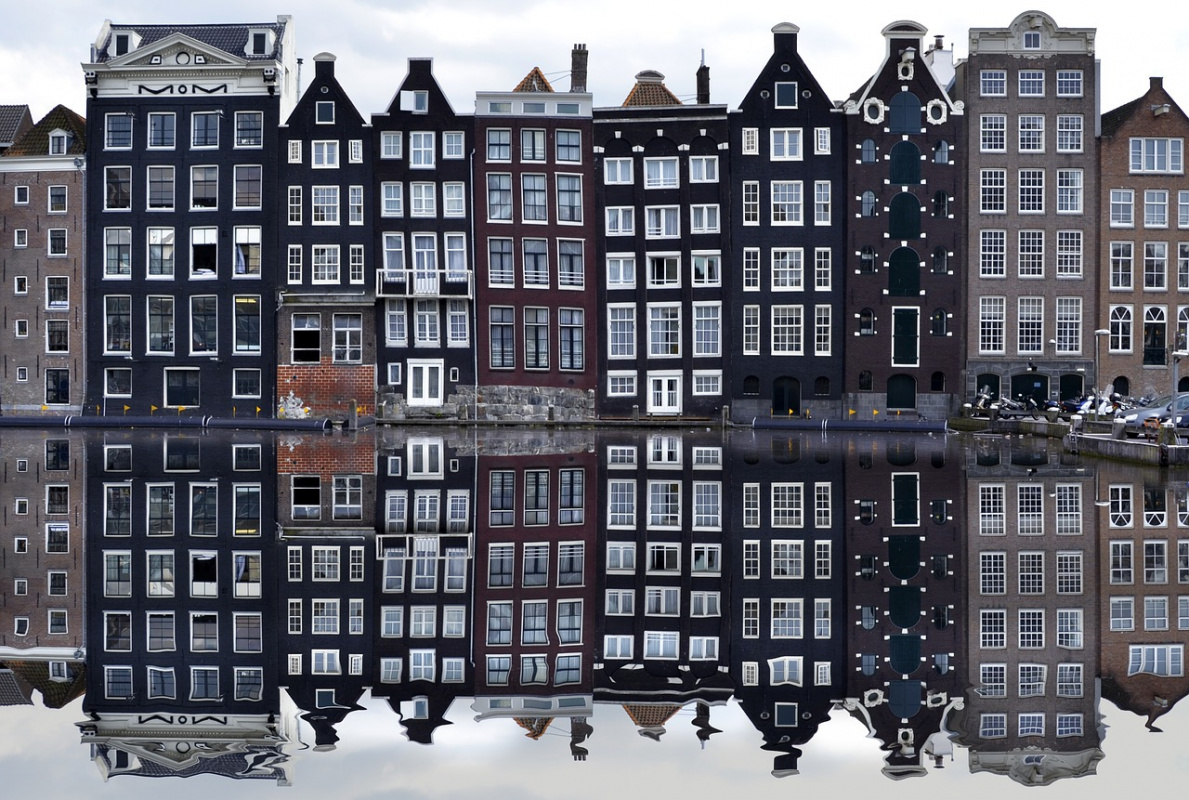 Iconic Amsterdam canal houses with their reflections in the water, a classic view to explore on a 2-day Amsterdam itinerary.