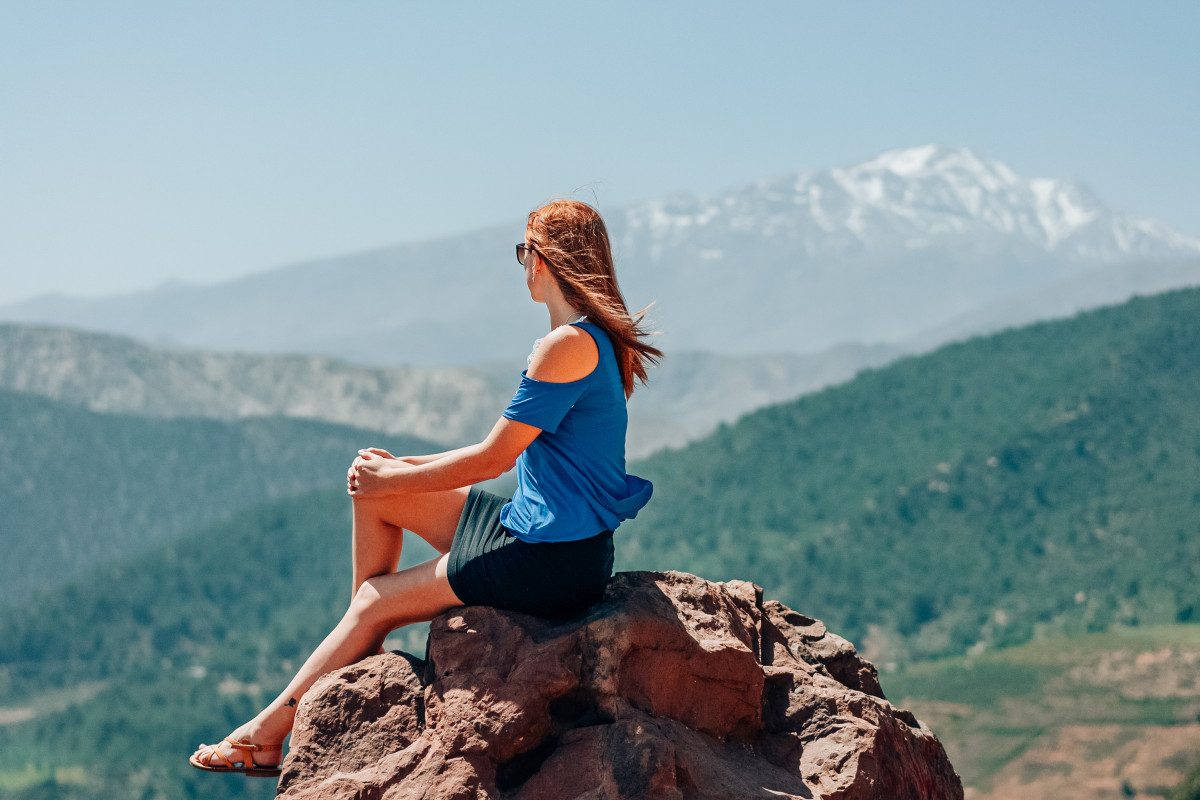 A woman contemplating the breathtaking scenery of the Atlas Mountains near Marrakech, a travel tip for those seeking majestic views is to take a balloon tour