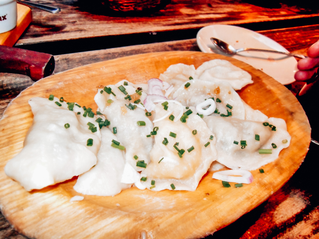 Hearty Polish pierogi dish served on a wooden plate, a delicious example of local cuisine one might enjoy while living in Poland.
