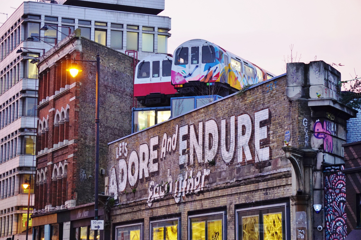 Colorful graffiti-adorned train carriages atop a building in vibrant Shoreditch, London, illustrating the city's dynamic street art scene, a must-see for culturally curious visitors and one of the many free things to do in London