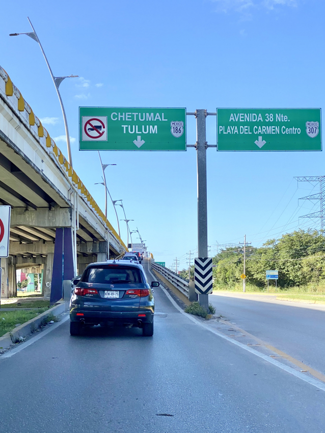Road view featuring direction signs to Tulum and Chetumal, common destinations for those renting cars in Mexico.

