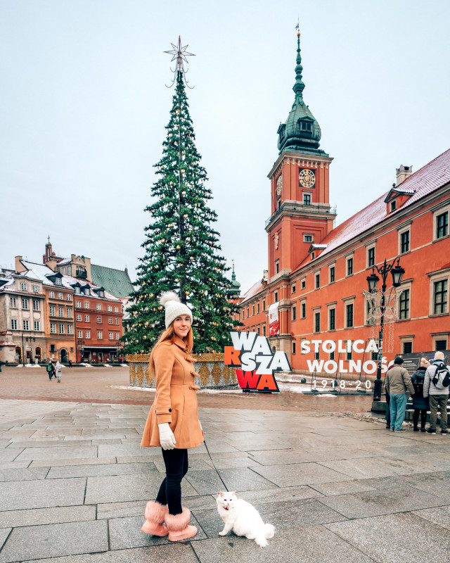 A girl with a cat on a leash in front of athe Royal Castle in Warsaw