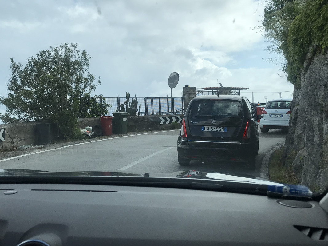 View from inside a rental car approaching a tight curve on an Italian country road, a common driving experience in Italy.
