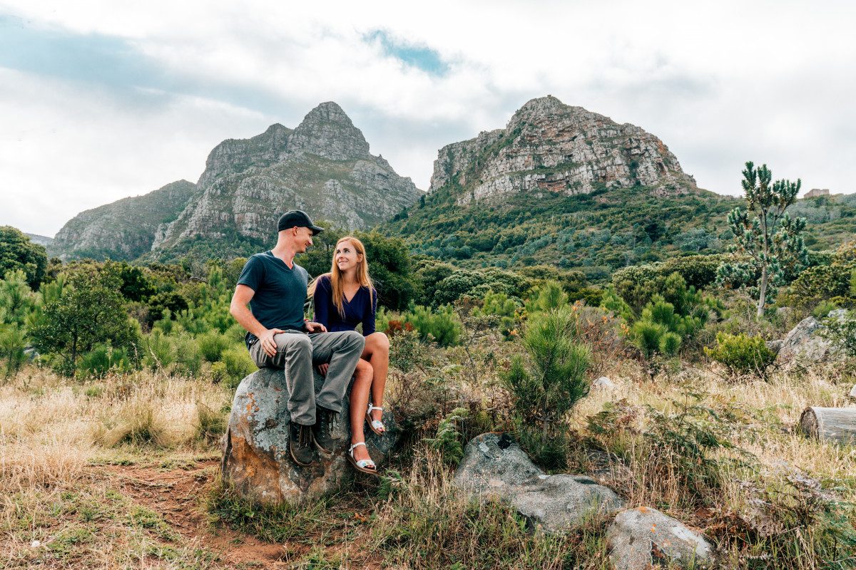 Couple enjoying a hike with a view of Cape Town's majestic mountains in the background, representing the adventurous outdoor activities that the city is known for.