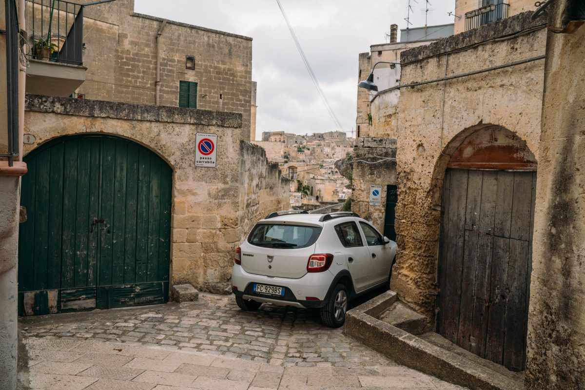 White rental car neatly parked in an old Italian town, a convenient way to visit historic sites while renting a car in Italy.