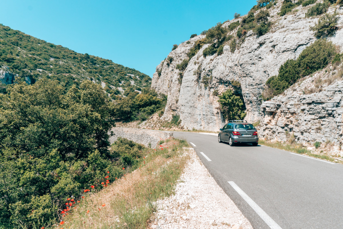 A car driving in France along cliffside roads with sweeping views and blossoming wildflowers