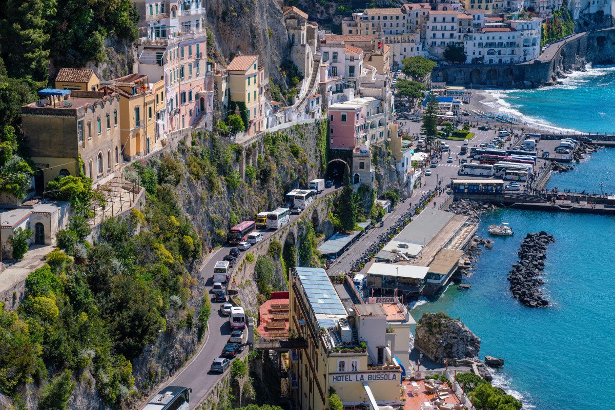 Breathtaking aerial view of a traffic-lined coastal road, a scenario often encountered when renting a car in Italy for a coastal drive.
