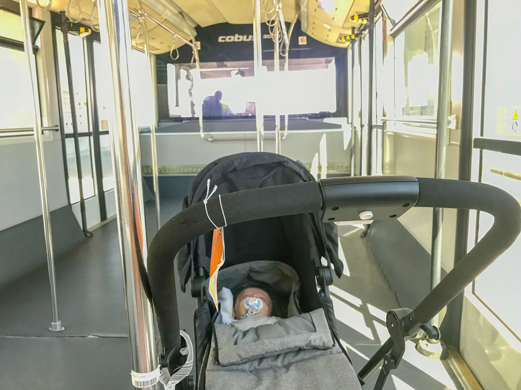 Baby in a travel stroller inside a public transport, highlighting the convenience of a compact stroller for city commuting.