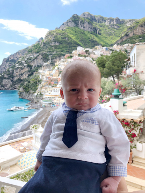 A baby dressed in a formal outfit with a bemused expression, after his first flight.
