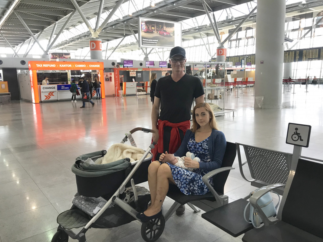 A family waiting at the airport with their baby and stroller before flying
