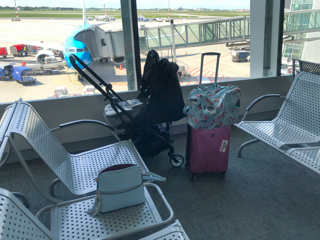 Stroller and luggage at an airport lounge, representing what to bring when flying with a baby