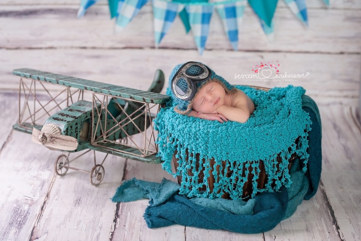 Newborn sleeping peacefully in a toy airplane, symbolizing the journey of flying with a baby.
