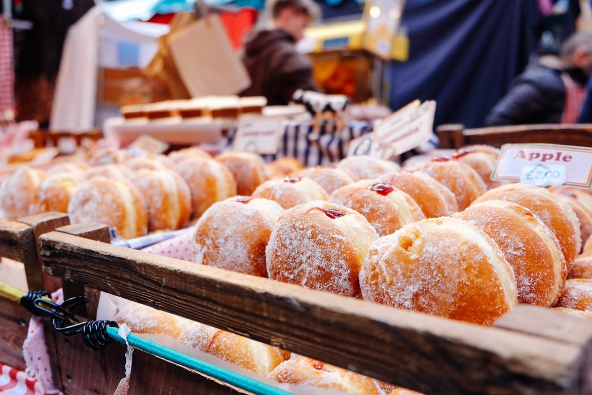 Traditional Polish pączki, sugared doughnuts filled with fruit, displayed at a market, a popular and sweet staple in Poland's pastry offerings