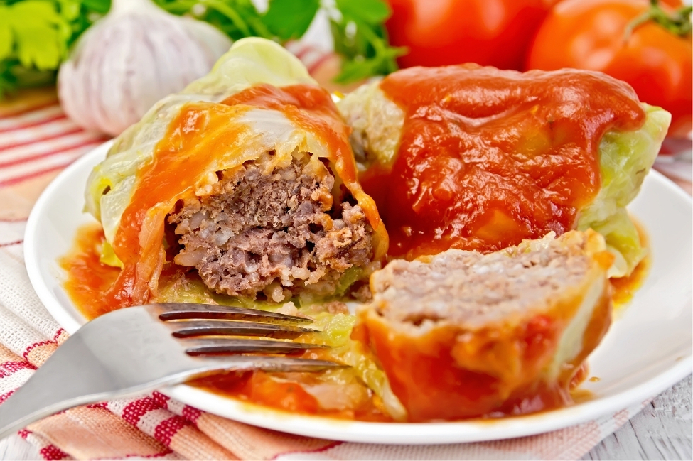 Stuffed cabbage rolls, known as Gołąbki, topped with tomato sauce, a staple in Polish cuisine, showcasing the heartiness of Eastern European meals.