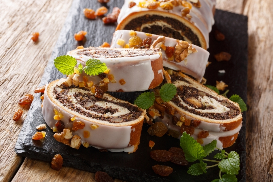 Slice of Polish Makowiec, a poppy seed roll cake, beautifully presented on a slate board, illustrating Poland's love for sweet, nutty baked goods.