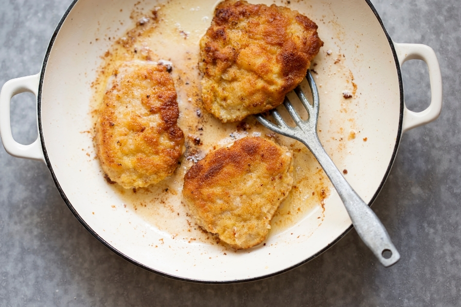 Golden fried Polish meat patties, known as Kotlety, in a cast iron pot, a beloved Polish dinner staple with roots in home-style cooking.