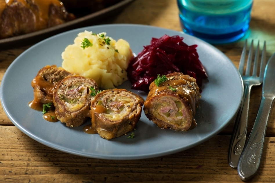 Slices of traditional Polish beef roulade, or zrazy, garnished with gravy, paired with mashed potatoes and beetroot, displaying Poland's hearty meat cuisine.
