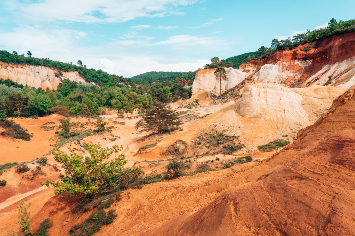 The ochre landscape of Roussillon offering a striking contrast with the lush greenery, a scenic drive destination in the French countryside that you can take if you decide to rent a car in France