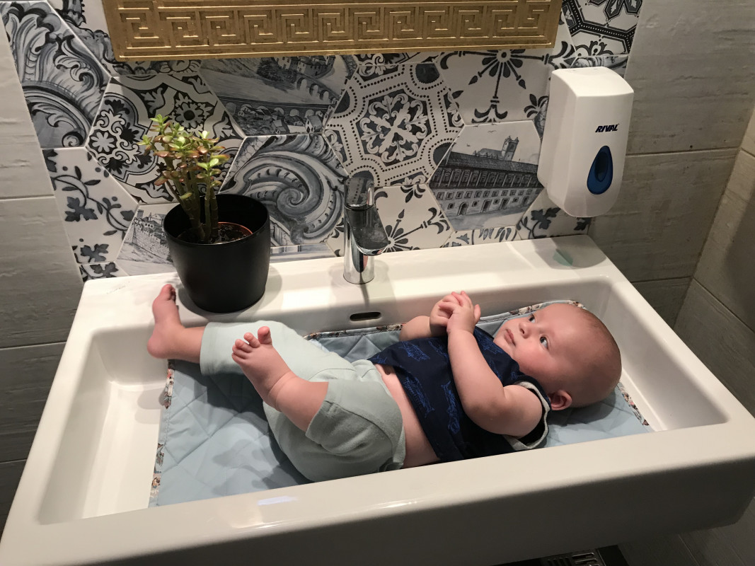 Innovative baby bath in a large sink with a picturesque Italian-style backsplash, as there are rarely change tables in Italy.
