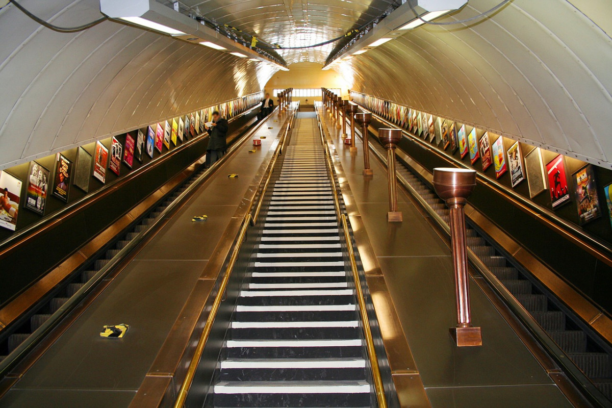 Long escalator leading deep underground in a London tube station, showcasing the vast network of public transport available to visitors, an essential tip for navigating the city efficiently