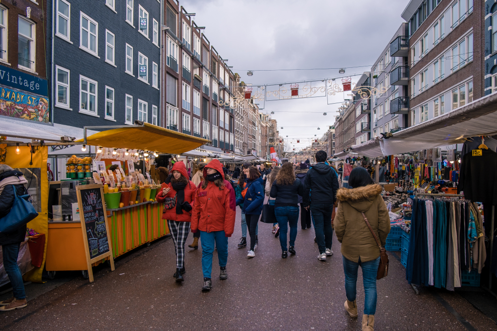 Bustling Albert Cuyp Market in Amsterdam, with locals and tourists shopping, a vibrant part of any Amsterdam itinerary.