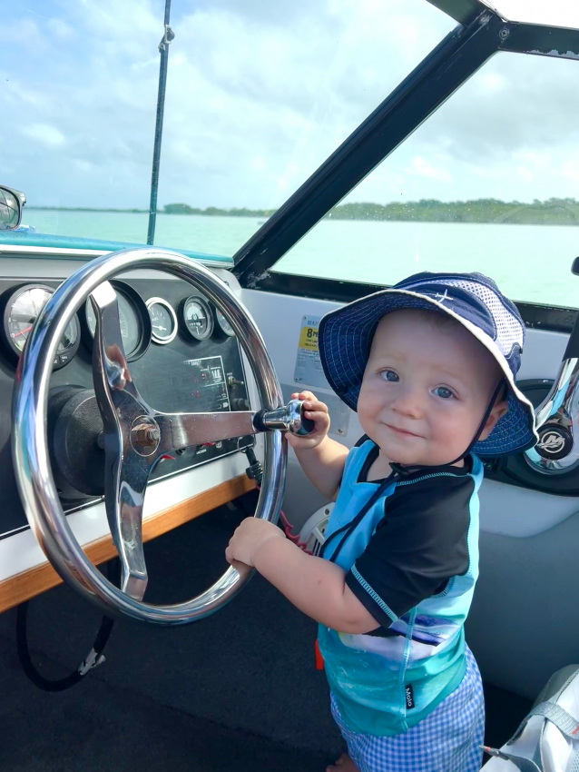 Baby enjoying a playful moment as a pretend skipper on a boat, making memories in Mexico.
