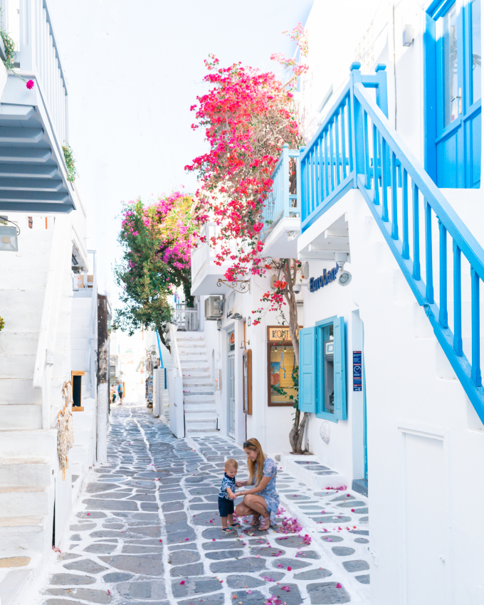 Mother and toddler on a charming street with vibrant flowers, a picturesque scene for family trips with a baby in Greece
