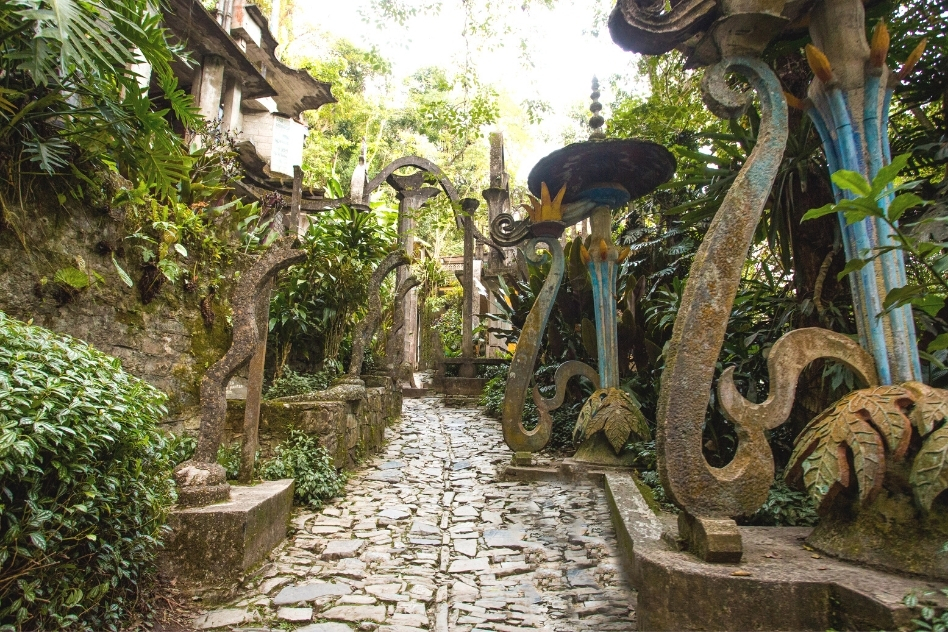 An enchanting stone pathway adorned with whimsical sculptures in a lush garden, a mystical addition to Mexico's unique places.
