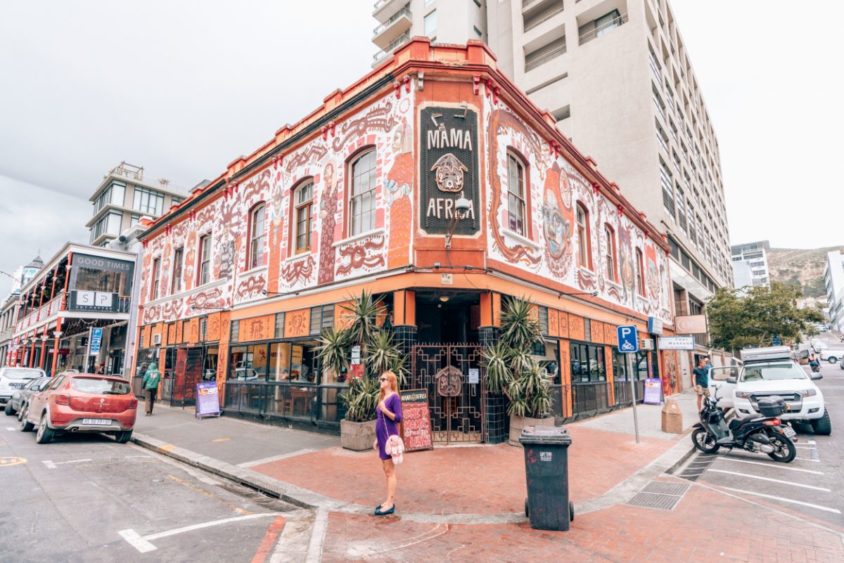 Tourist standing outside the vibrant Mama Africa restaurant in Cape Town, known for its lively atmosphere and authentic African cuisine, a culinary highlight for visitors.