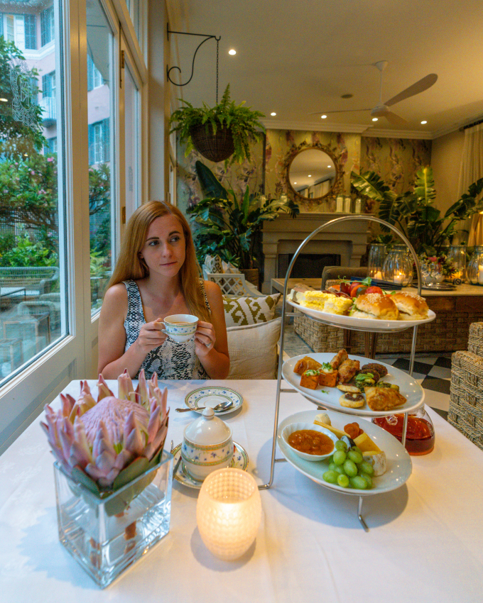 High tea experience in Cape Town, with a woman enjoying a selection of gourmet bites, highlighting the culinary delights and sophisticated dining options the city has to offer.