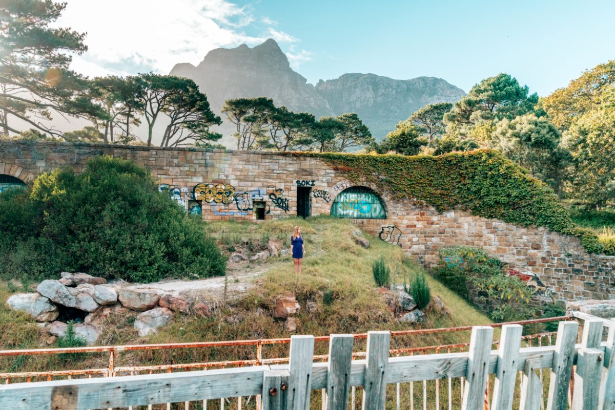 Woman exploring the graffiti-adorned ruins at former Groote Schuur Zoo, Cape Town, offering a unique experience for those seeking unusual things to do in Cape Town.