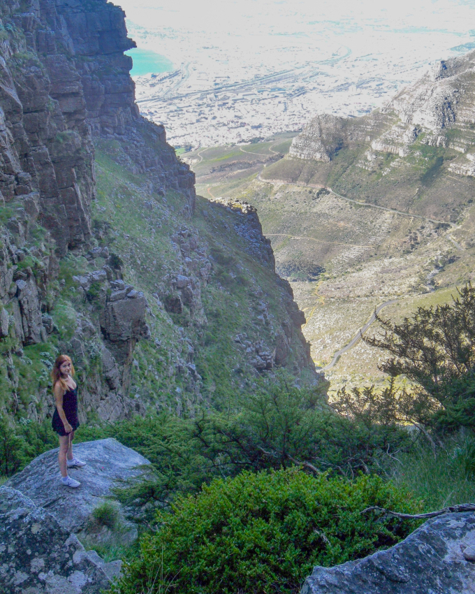 Hiker standing on the edge of Table Mountain overlooking Cape Town, showcasing the hiking opportunities and breathtaking views available in one of Cape Town's main attractions.