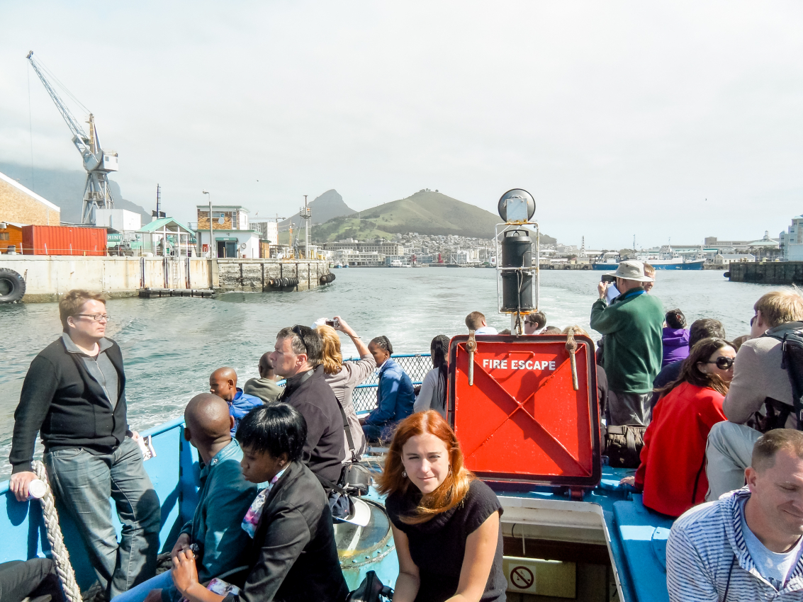Passenger on a boat tour departing from Cape Town’s harbor, with the cityscape and Table Mountain in the distance, a perfect way to experience the city’s maritime charm.