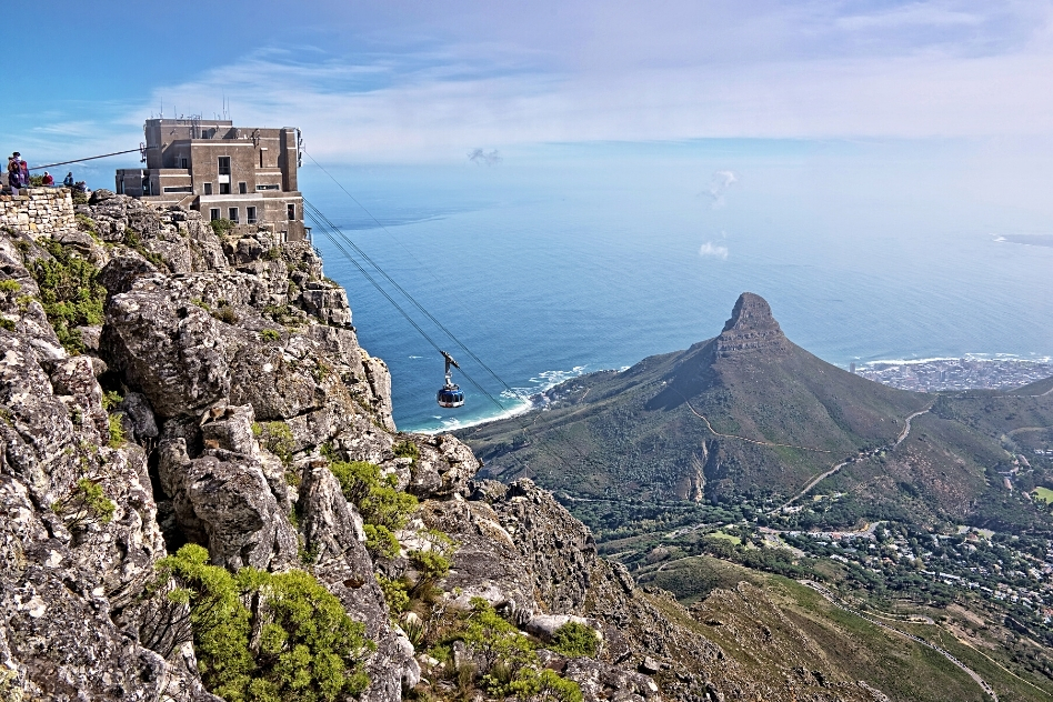 Aerial view of Table Mountain Cableway in Cape Town, with the car ascending against a backdrop of the city's panoramic coastline, one of the top things to do in Cape Town.