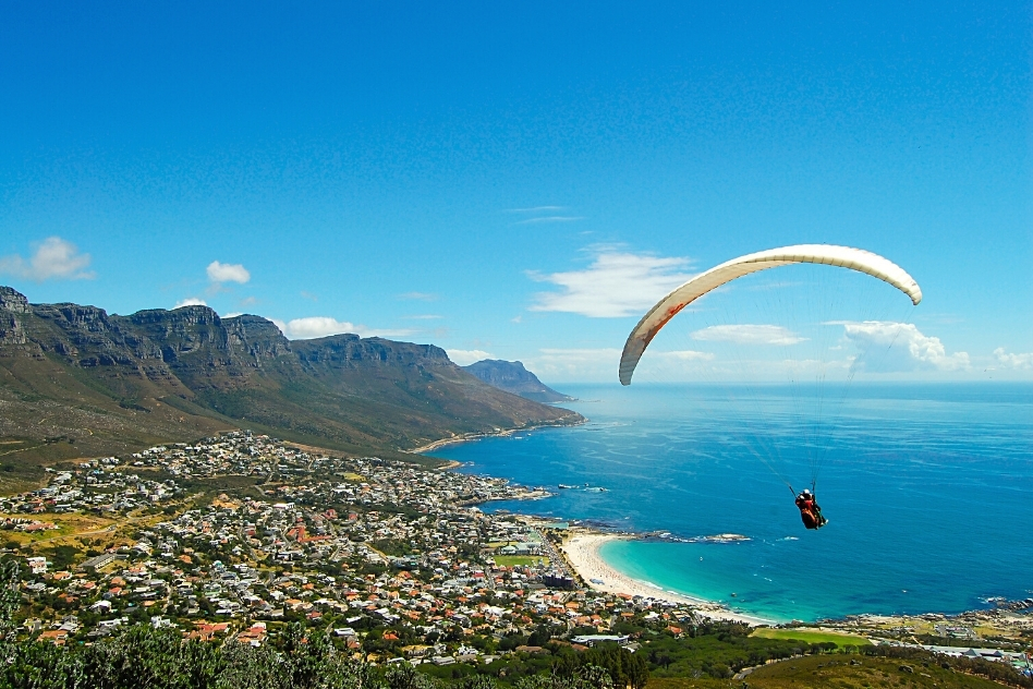 Paraglider soaring above Cape Town with a stunning view of the Twelve Apostles and the Atlantic Ocean, offering an exhilarating activity for thrill-seekers visiting the city.