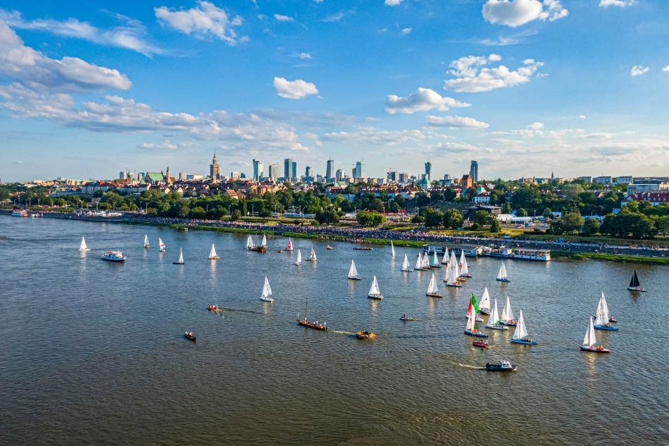 Boats sailing on the Vistula River with a panoramic view of Warsaw, a serene backdrop for riverside accommodations.
