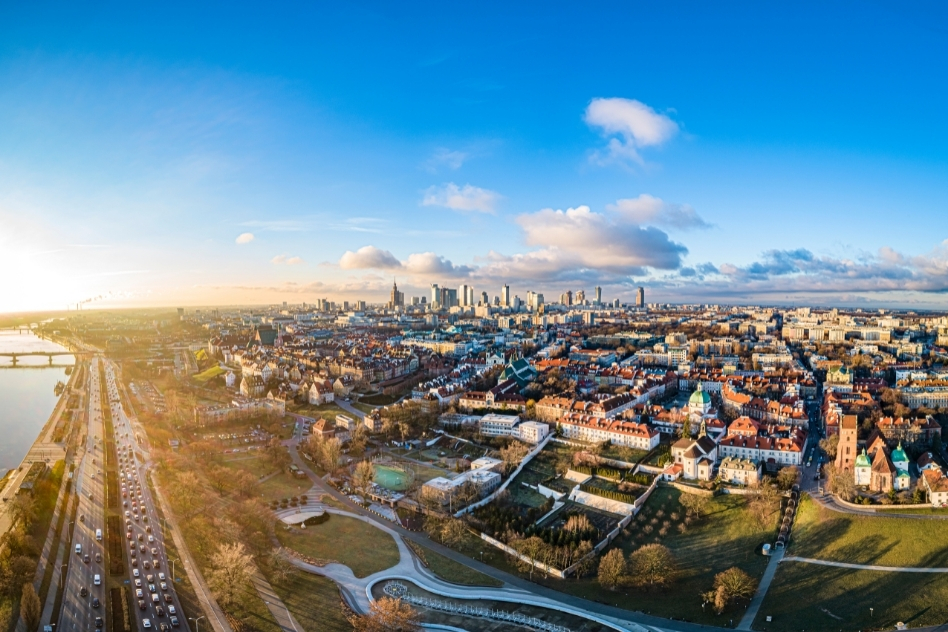 Golden hour aerial shot of Warsaw skyline showing urban and park areas, illustrating the variety of places to stay in Warsaw.
