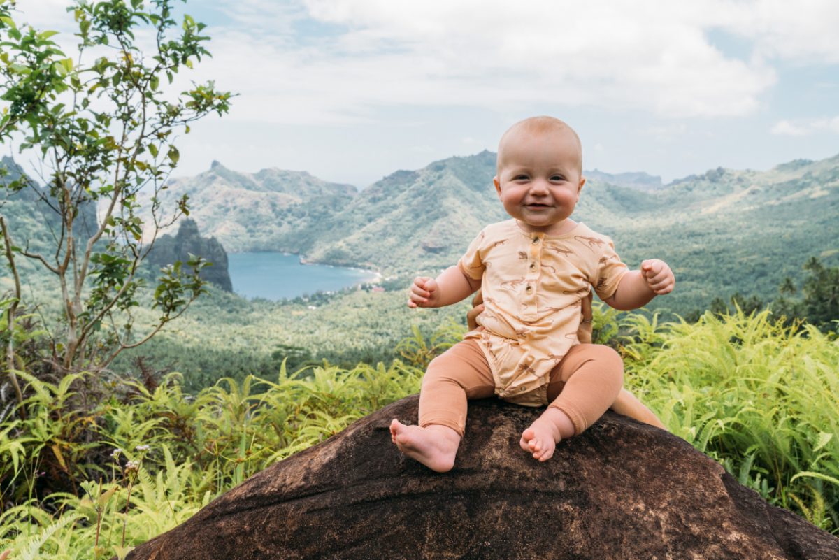 French Polynesia with baby. Smiling baby with a view of Nuku Hiva