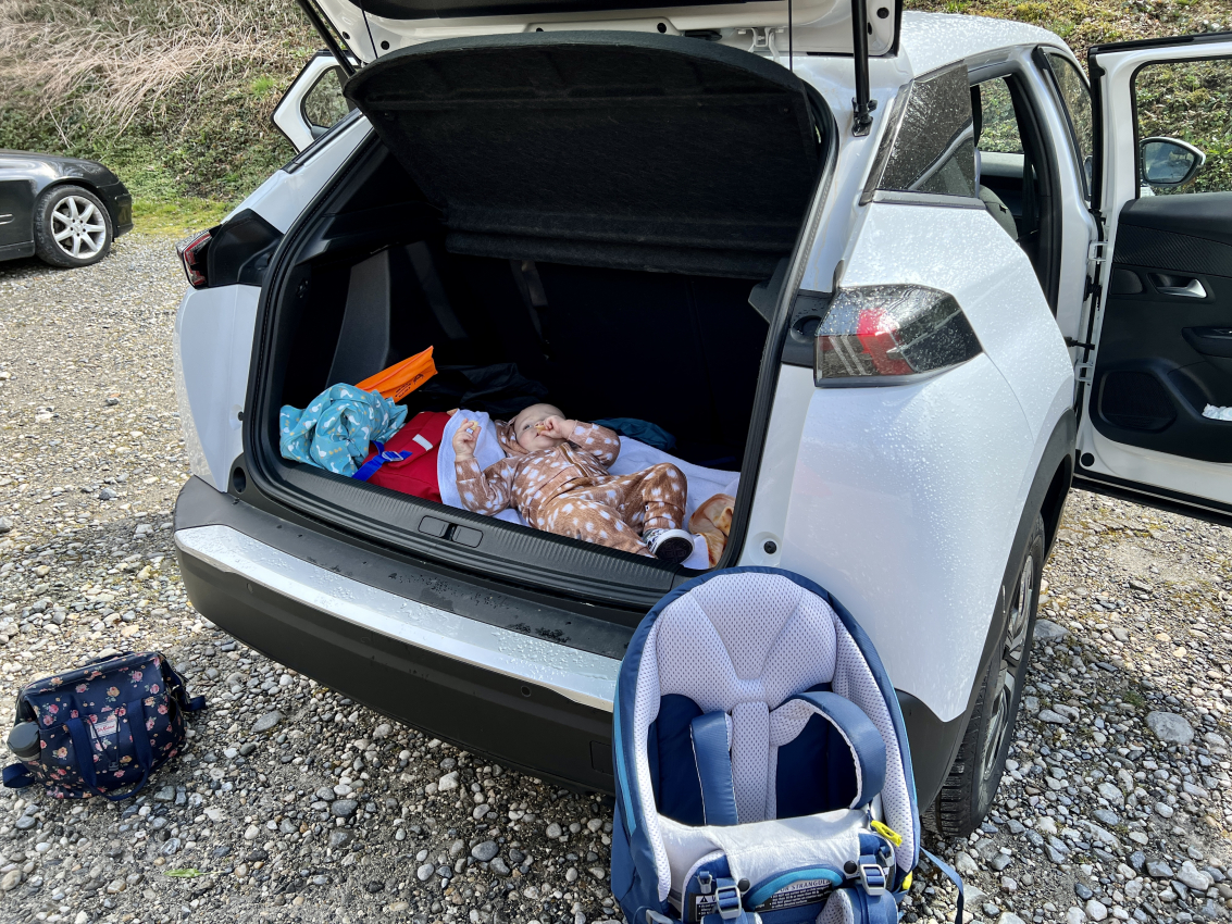 Child resting in the trunk of an SUV during a road trip, portraying the impromptu nap times when traveling in France with a baby.
